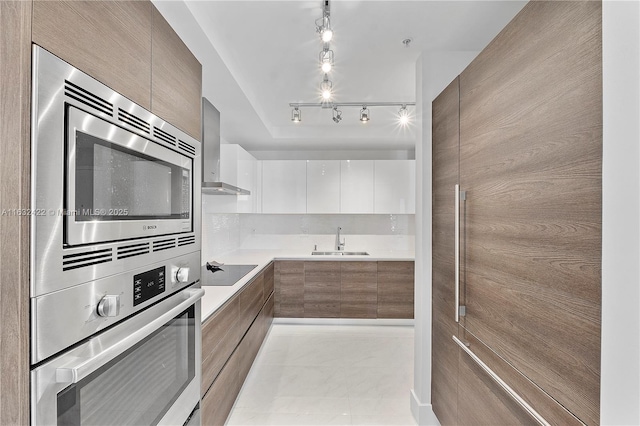 kitchen featuring sink, white cabinetry, appliances with stainless steel finishes, light tile patterned floors, and wall chimney exhaust hood