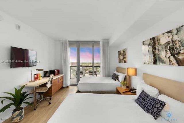 bedroom with access to outside, light wood-type flooring, and expansive windows