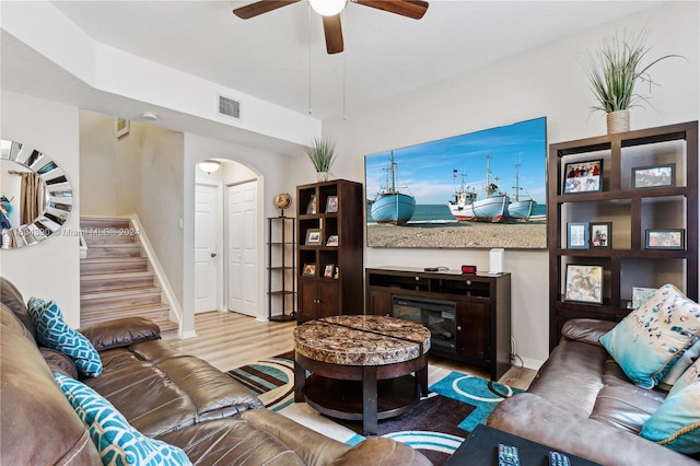 living room featuring arched walkways, wood finished floors, visible vents, a ceiling fan, and stairway