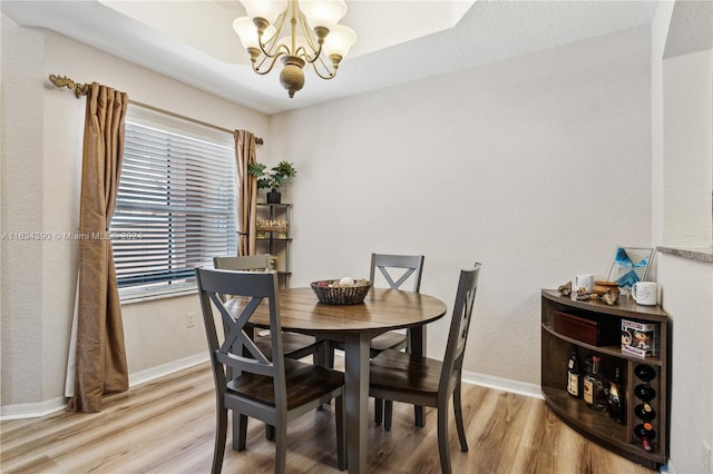 dining room with a notable chandelier, baseboards, and wood finished floors