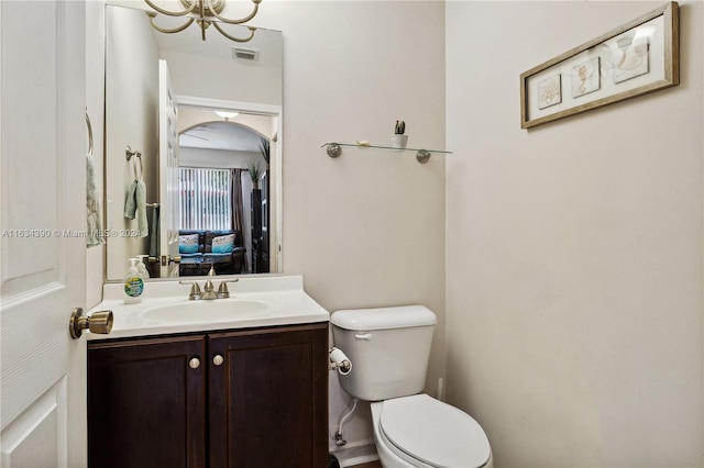 half bathroom featuring toilet, ensuite bath, visible vents, and vanity