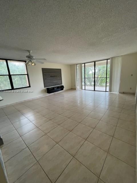 unfurnished living room featuring a textured ceiling, expansive windows, ceiling fan, and light tile patterned flooring