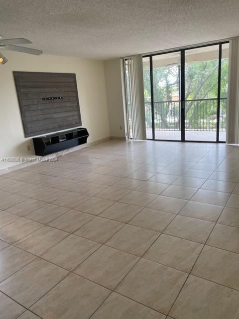 unfurnished living room featuring light tile patterned flooring, ceiling fan, and a textured ceiling