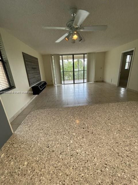 unfurnished living room featuring tile patterned flooring, ceiling fan, and a textured ceiling