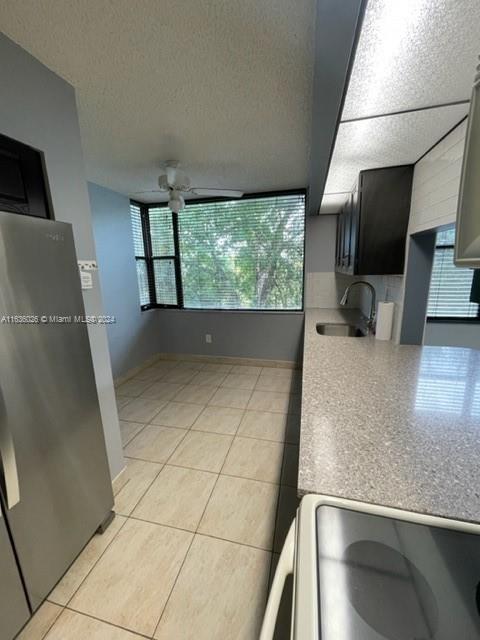 kitchen with stainless steel refrigerator, sink, gray cabinetry, light tile patterned floors, and ceiling fan