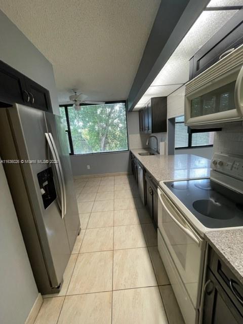 kitchen featuring tasteful backsplash, sink, a textured ceiling, light tile patterned flooring, and stainless steel appliances