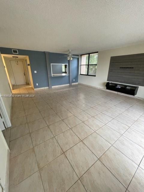 unfurnished living room featuring a textured ceiling, ceiling fan, and tile patterned floors