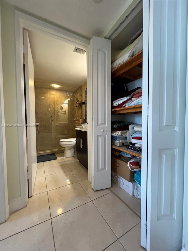 bathroom featuring vanity, tile patterned floors, toilet, and walk in shower