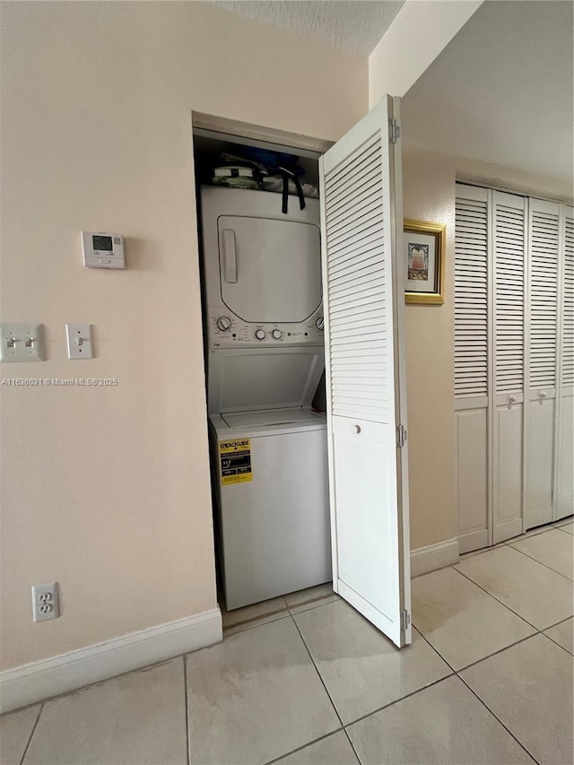 clothes washing area featuring stacked washer and clothes dryer and light tile patterned floors