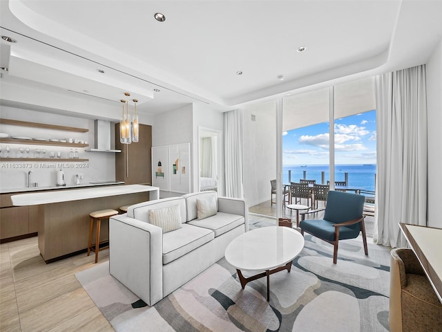 living room featuring a raised ceiling and a water view