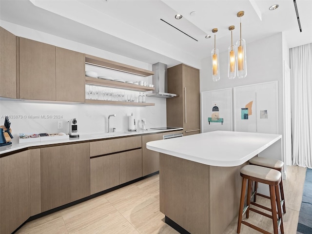 kitchen featuring black electric cooktop, sink, wall chimney range hood, a kitchen island, and hanging light fixtures