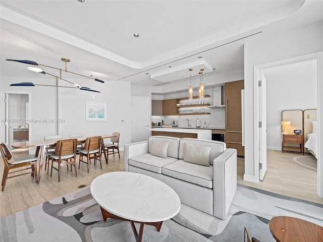 living room featuring a raised ceiling, light hardwood / wood-style flooring, and an inviting chandelier