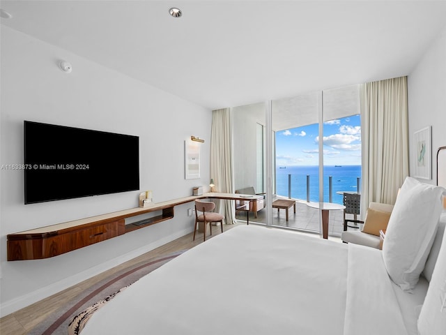 bedroom with a water view, wood-type flooring, and access to outside