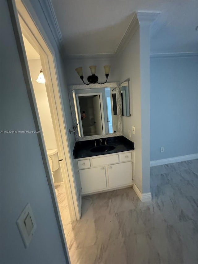 bathroom with toilet, vanity, and ornamental molding