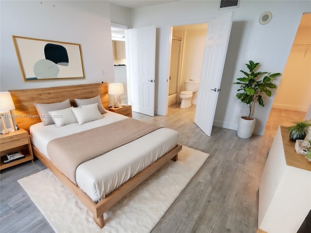 bedroom featuring connected bathroom and light hardwood / wood-style floors