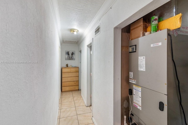 hallway with heating unit, ornamental molding, light tile patterned floors, and a textured ceiling