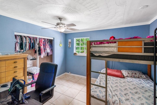 bedroom with a closet, light tile patterned floors, and ceiling fan