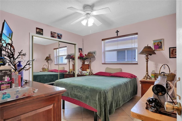 bedroom with light tile patterned flooring, a textured ceiling, a closet, and ceiling fan