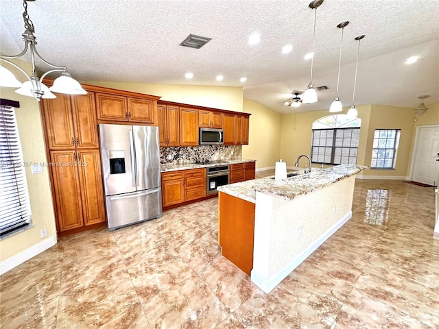 kitchen with tasteful backsplash, an island with sink, hanging light fixtures, and appliances with stainless steel finishes