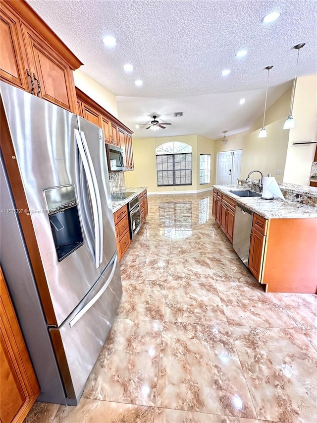 kitchen with pendant lighting, sink, ceiling fan, a textured ceiling, and stainless steel appliances