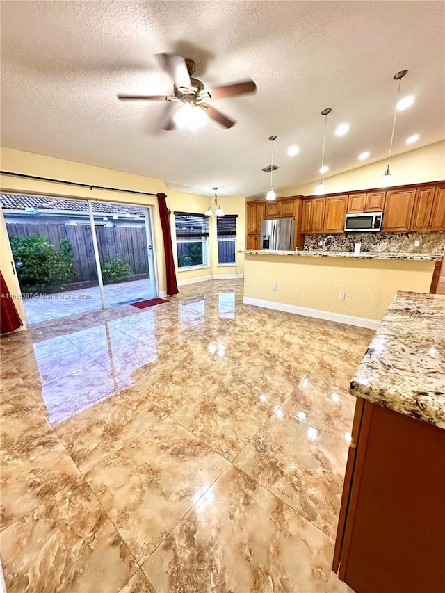 kitchen with a textured ceiling, lofted ceiling, stainless steel appliances, and decorative light fixtures