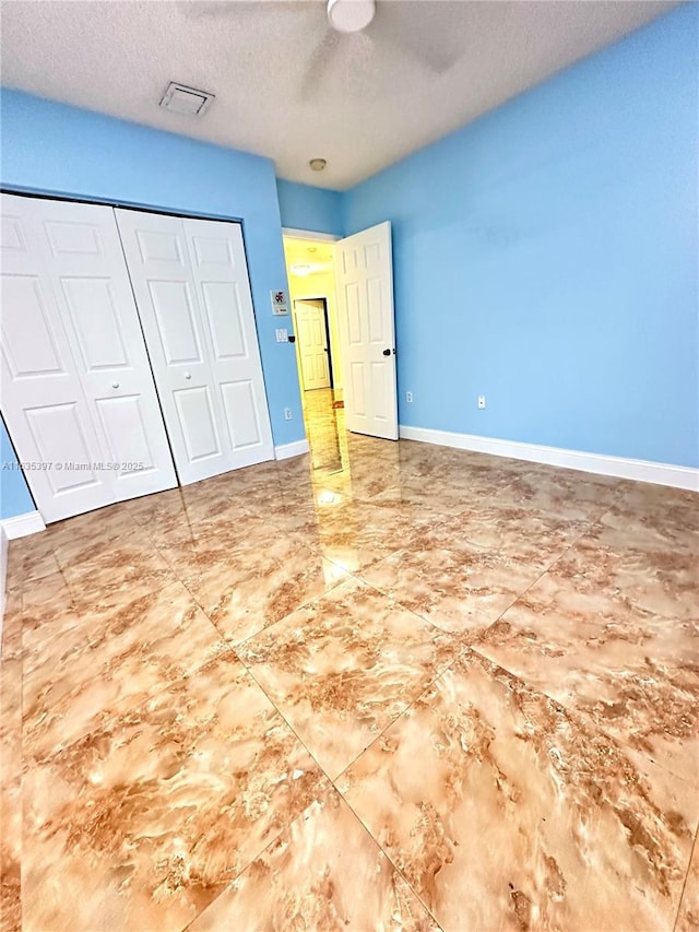 unfurnished bedroom featuring ceiling fan, a textured ceiling, and a closet