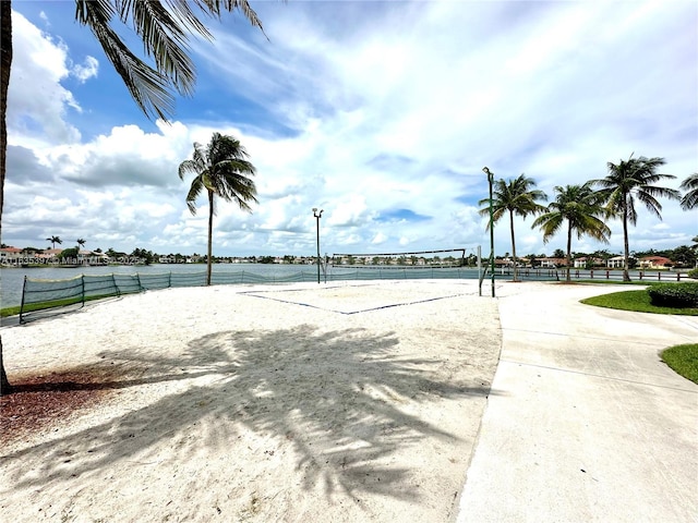 surrounding community with a water view and volleyball court