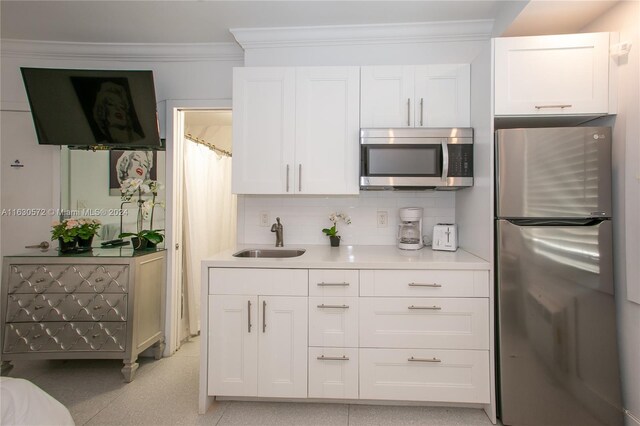 kitchen with decorative backsplash, stainless steel appliances, ornamental molding, and white cabinets