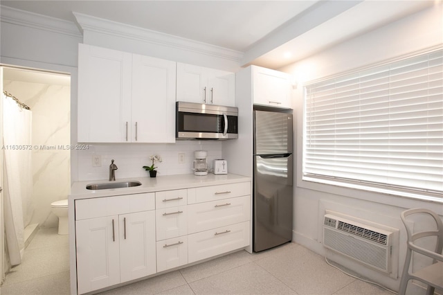 kitchen featuring appliances with stainless steel finishes, tasteful backsplash, sink, crown molding, and white cabinetry