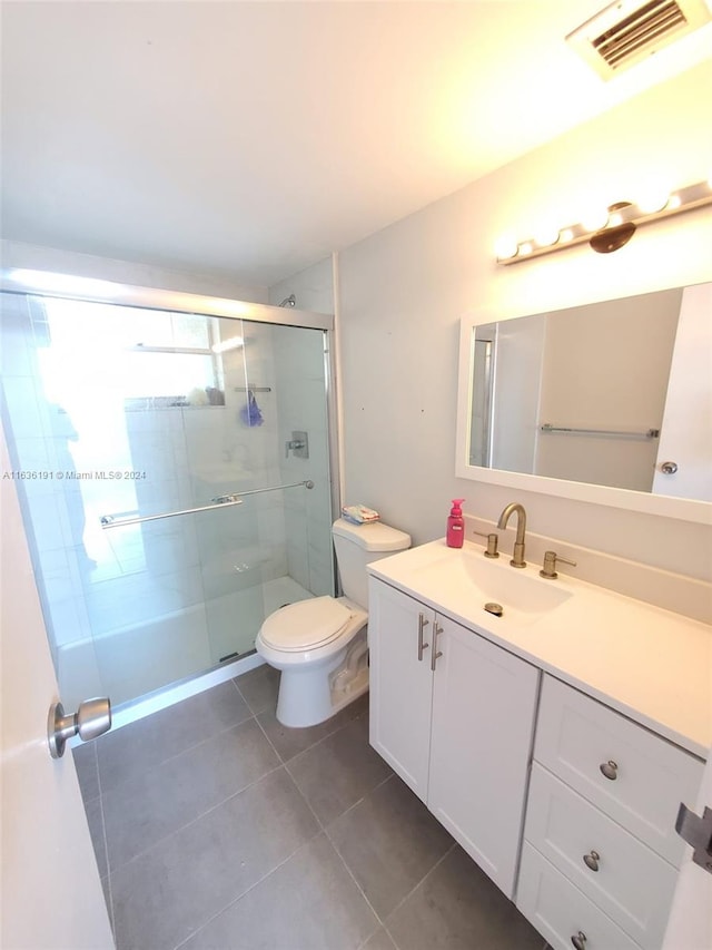 bathroom with vanity, a shower with shower door, toilet, and tile patterned flooring