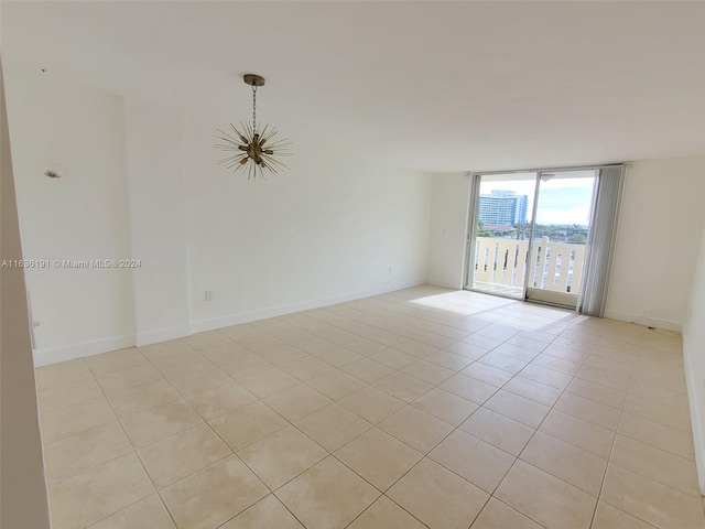 7900 Tatum Waterway Dr Unit 502, Miami Beach, FL 33141 - empty room with light tile patterned floors, baseboards, a wall of windows, and a notable chandelier