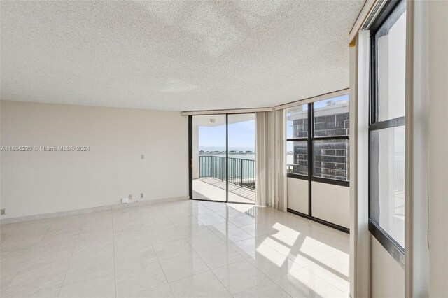 unfurnished room featuring a wall of windows, light tile patterned floors, and a textured ceiling