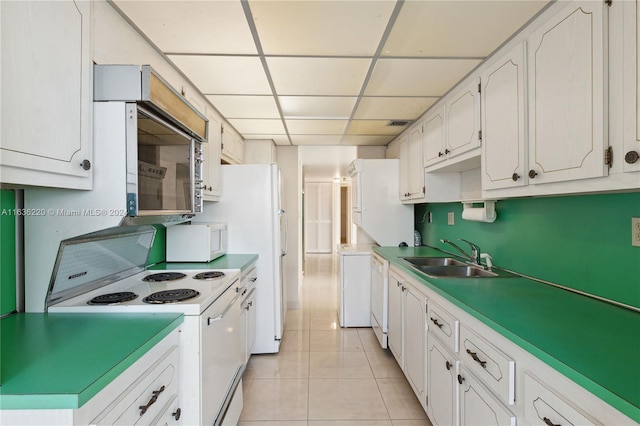 kitchen with a drop ceiling, white cabinets, white appliances, sink, and light tile patterned floors