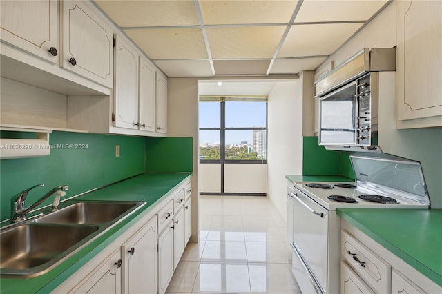 kitchen with sink, light tile patterned floors, electric stove, and white cabinets