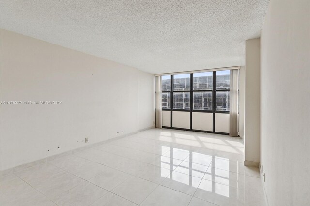 spare room featuring a textured ceiling, light tile patterned floors, and floor to ceiling windows