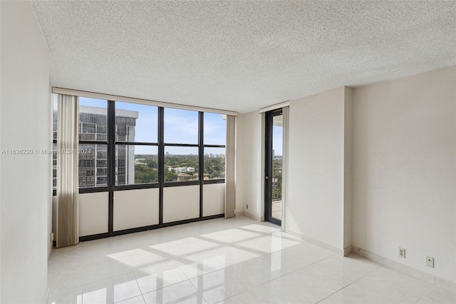 unfurnished room with expansive windows, a textured ceiling, and light tile patterned floors