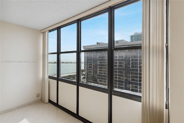 spare room with a water view and light tile patterned floors