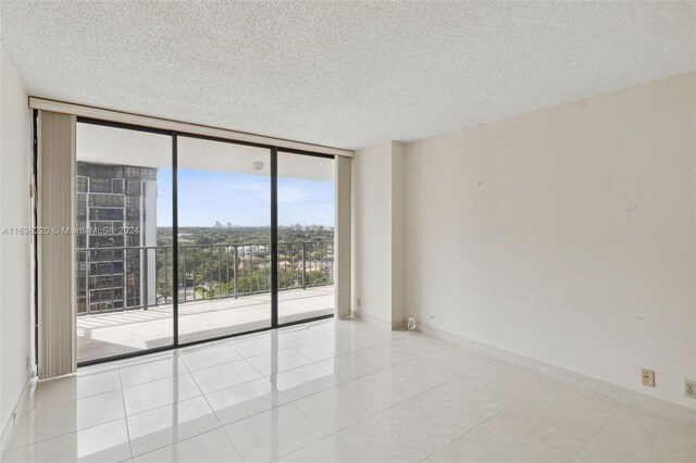 spare room featuring light tile patterned flooring, a textured ceiling, and expansive windows