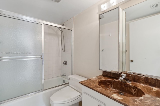 full bathroom with vanity, enclosed tub / shower combo, and toilet