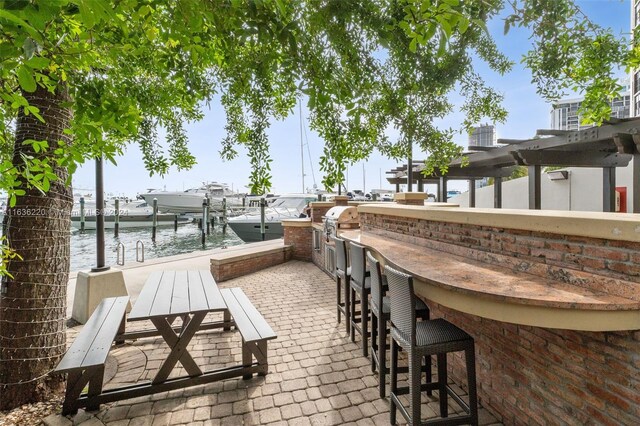 view of patio / terrace featuring exterior bar, a boat dock, and a water view