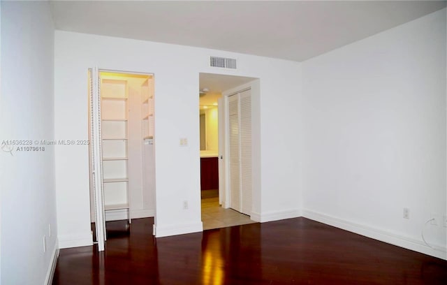 unfurnished bedroom with baseboards, visible vents, wood finished floors, and a closet