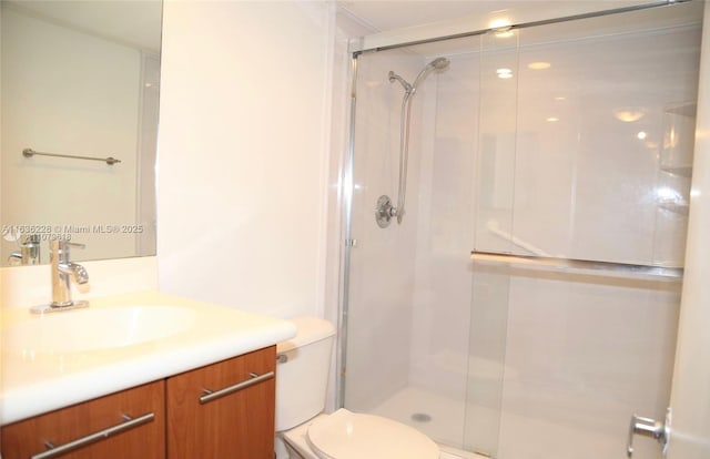 bathroom featuring toilet, vanity, and a shower stall