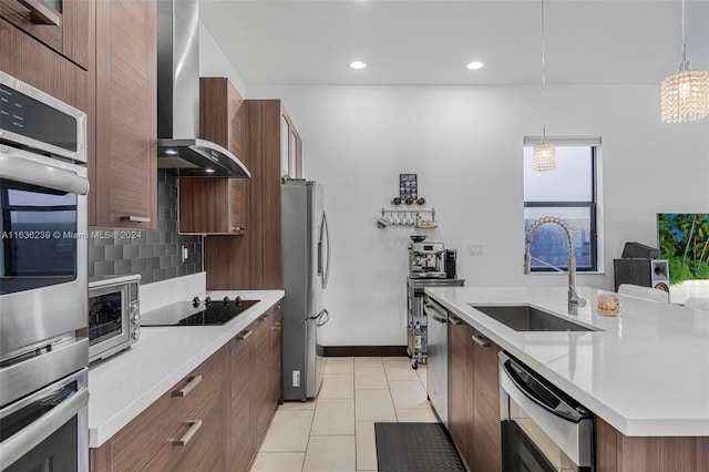 kitchen with wall chimney range hood, stainless steel appliances, sink, light tile patterned floors, and backsplash