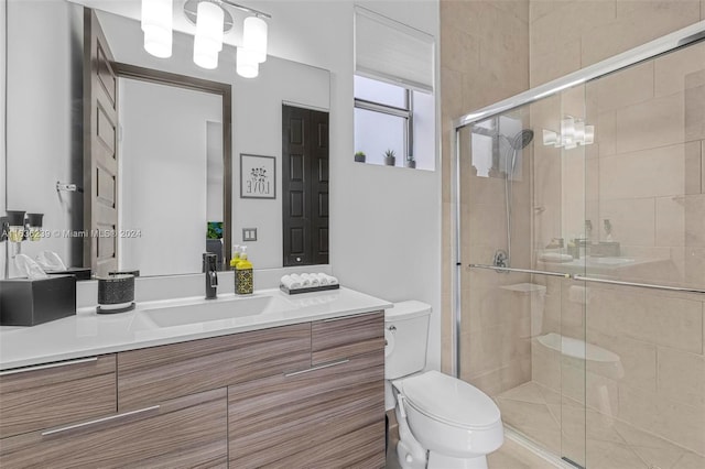 bathroom with vanity, a shower with door, and toilet