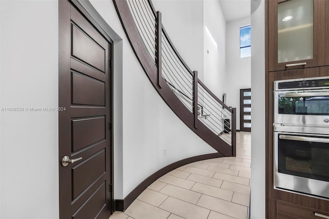 interior space featuring double oven, dark brown cabinets, and light tile patterned floors