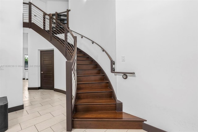 staircase with light tile patterned flooring and a high ceiling