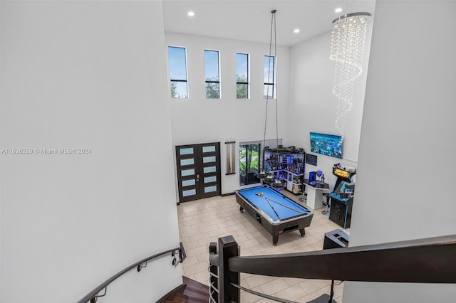 exercise room with light tile patterned flooring, pool table, a chandelier, and a high ceiling