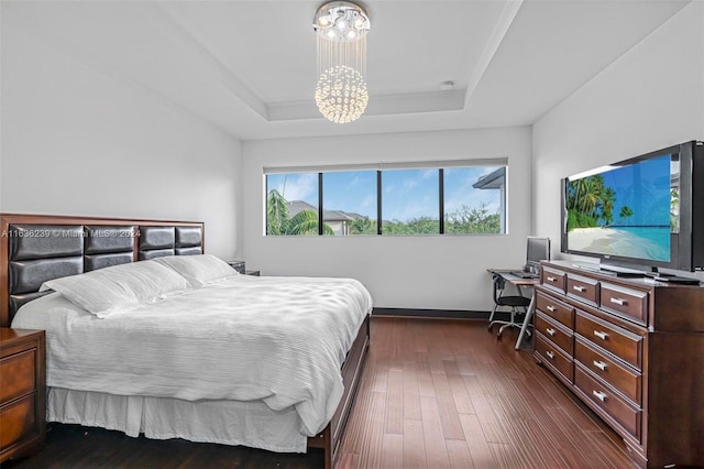 bedroom featuring a raised ceiling, dark hardwood / wood-style flooring, and an inviting chandelier