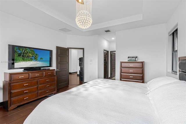 bedroom with dark hardwood / wood-style flooring, a chandelier, and a tray ceiling