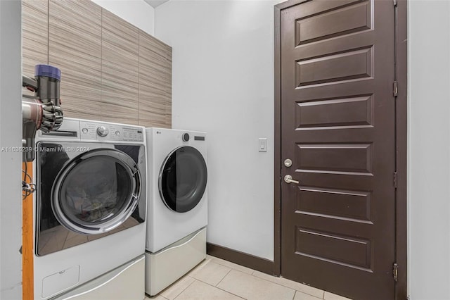 clothes washing area featuring light tile patterned flooring and washer and clothes dryer